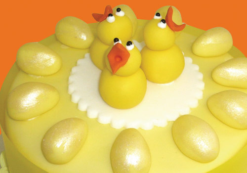A cake shaped like egss and ducks in yellow iciong